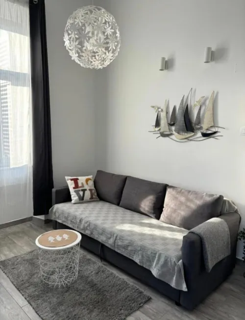 The light-filled studio with a grey sofa, small coffee table and sailboat wall art